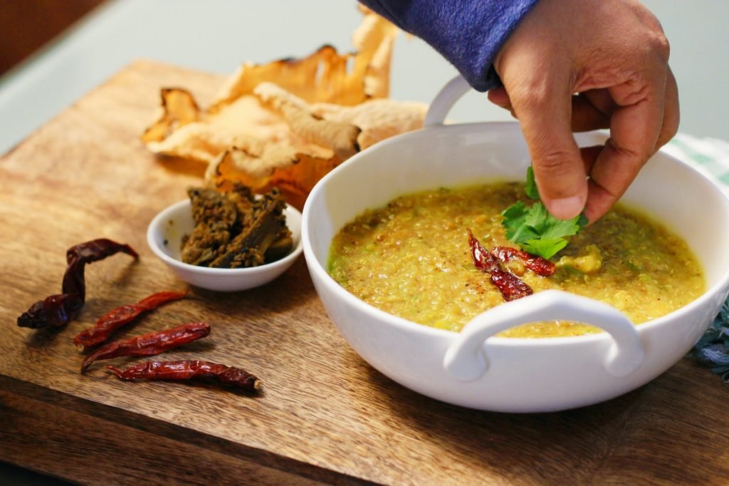 A Person Adding Coriander Leaves On A Spicy Khichdi